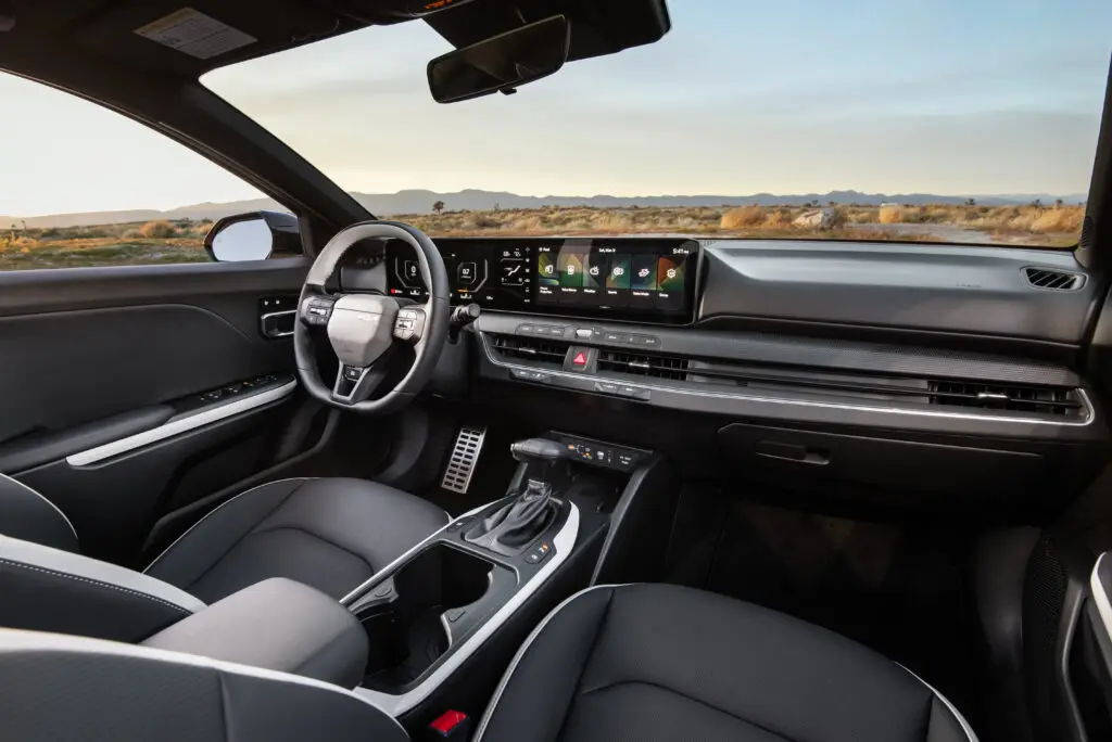 Interior moderno de un coche con pantalla táctil y volante elegante.