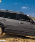 Camioneta SUV sobre tierra con una rueda levantada.