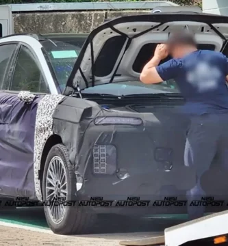 Auto camuflado cargando batería, ingeniero examinando el capó.