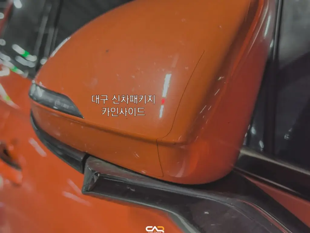 Espejo retrovisor lateral de un automóvil naranja con texto coreano.
