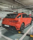 Camioneta Porsche Cayenne naranja estacionada en un parking subterráneo.