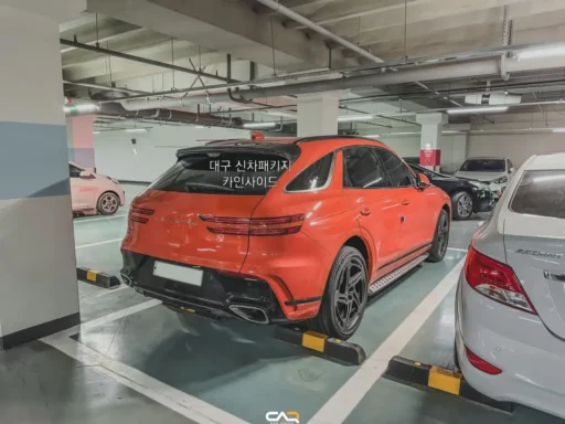 Camioneta Porsche Cayenne naranja estacionada en un parking subterráneo.