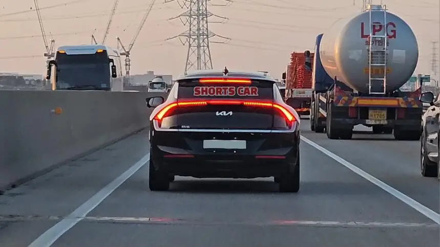 Auto negro en carretera, con el cartel "SHORTS CAR".