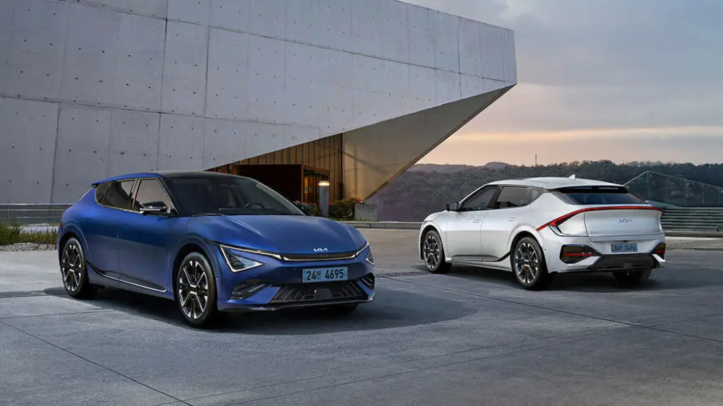 Dos autos eléctricos Kia, azul y blanco, estacionados.