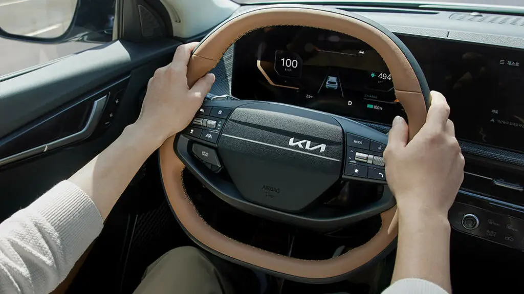 Manos sujetando volante de un auto moderno marca Kia.