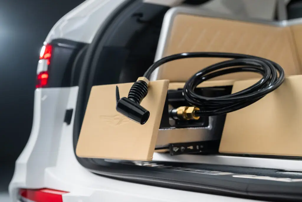 Carga de vehículo eléctrico con cable y enchufe en maletero.