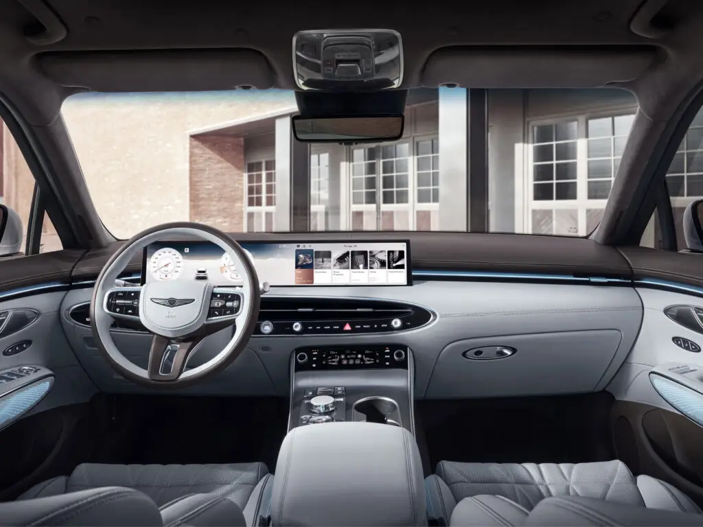 Interior lujoso de un automóvil con volante y pantallas digitales.