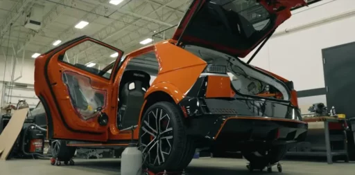 Vehículo deportivo naranja desmontado en un taller.
