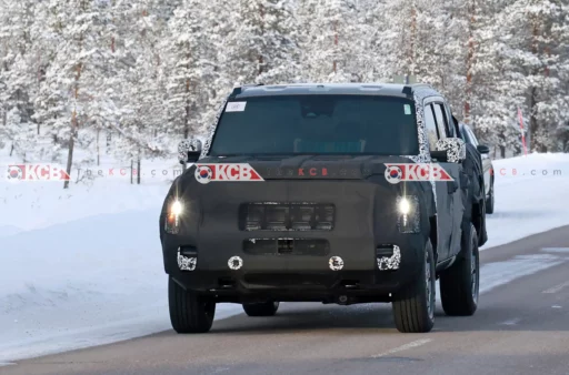 Un vehículo camuflado conduciendo en carretera nevada.