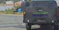 Camioneta negra cubierta en camino rural, logo HEALER TV visible.