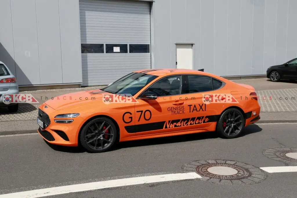 Coche naranja tipo taxi de carreras, Genesis G70, en la calle.