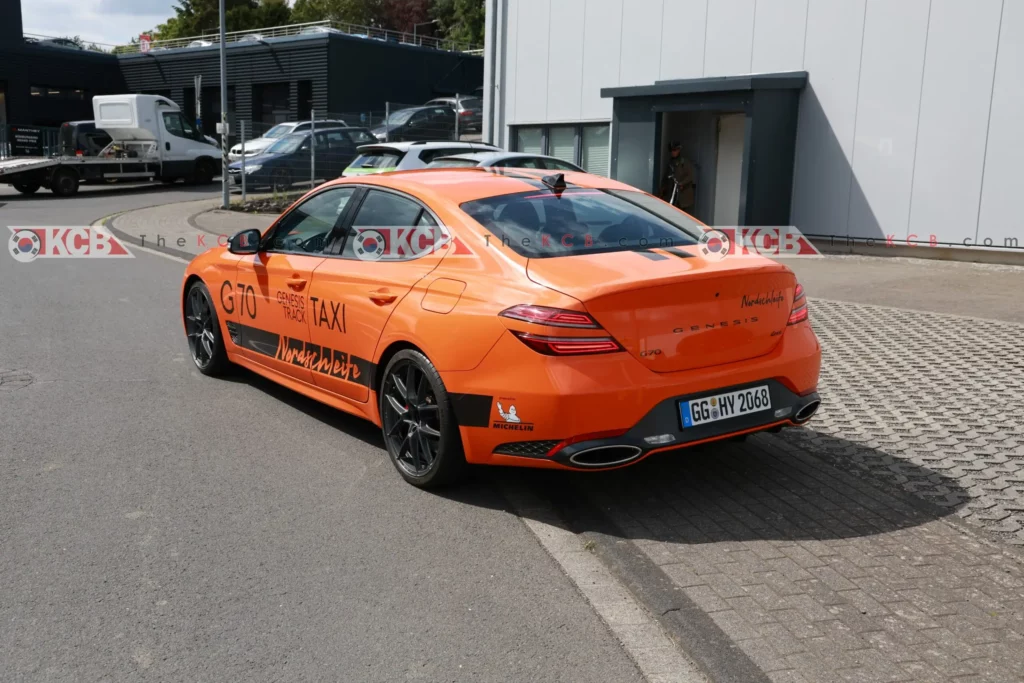 Coche deportivo naranja con publicidad en un entorno industrial.