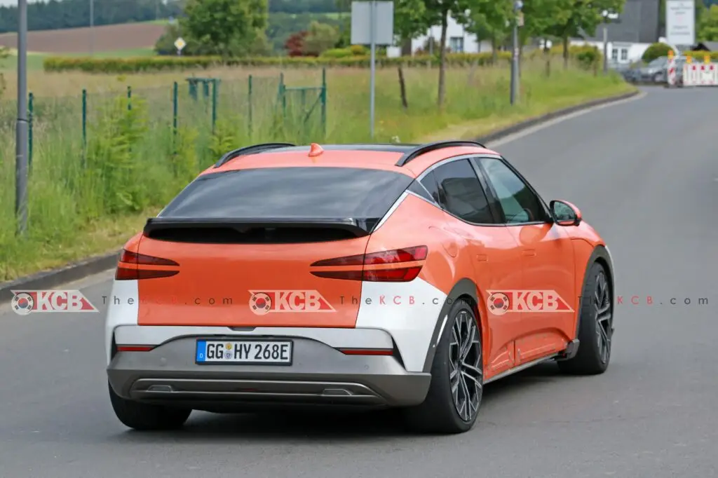 Auto naranja y plateado en una carretera, matrícula europea.