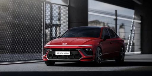 Coche rojo deportivo estacionado junto a una reja.