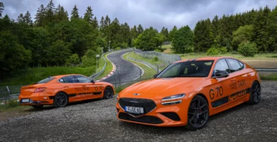 Dos coches deportivos naranjas estacionados junto a una pista.