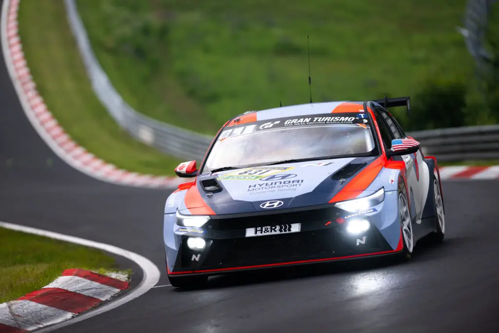 Auto de carreras Hyundai en una pista curva y verde.