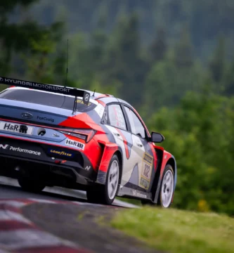 Coche de carreras Hyundai en una pista rodeada de árboles.