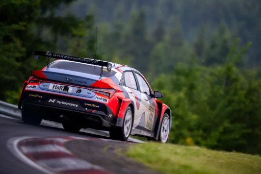 Coche de carreras Hyundai en una pista rodeada de árboles.