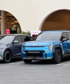 Dos autos eléctricos estacionados junto a cargadores de Tesla.