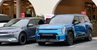 Dos autos eléctricos estacionados junto a cargadores de Tesla.