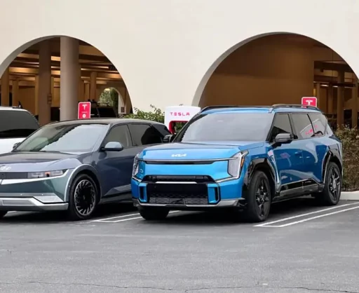 Dos autos eléctricos estacionados junto a cargadores de Tesla.