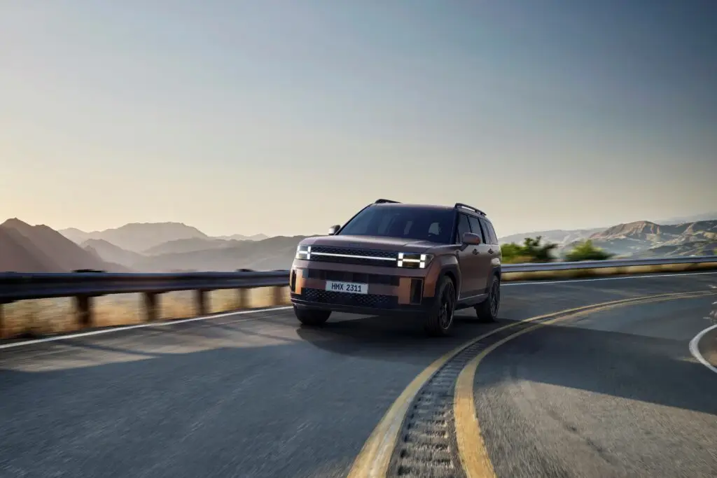 SUV moderno conduciendo en una carretera de montaña al atardecer.