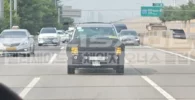 Autos circulando por una carretera con vegetación al fondo.