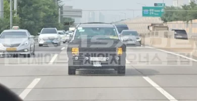 Autos circulando por una carretera con vegetación al fondo.