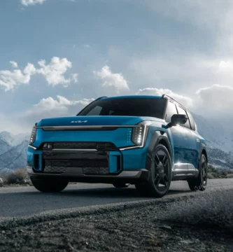 Auto azul en una carretera con montañas nevadas al fondo.