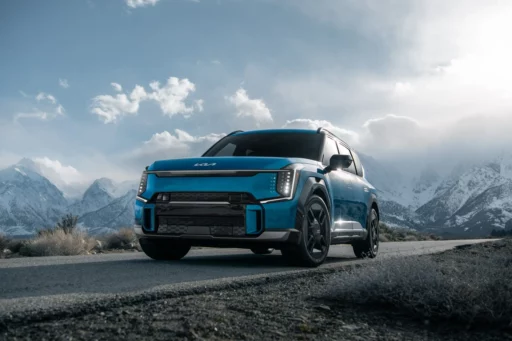 Auto azul en una carretera con montañas nevadas al fondo.