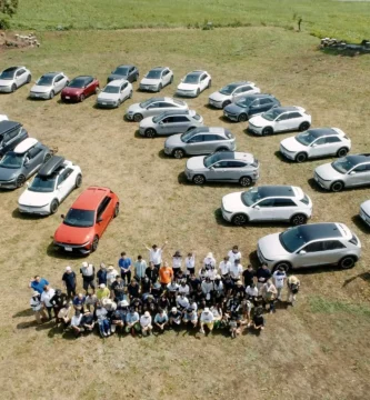 Grupo de personas y muchos autos en una campa.