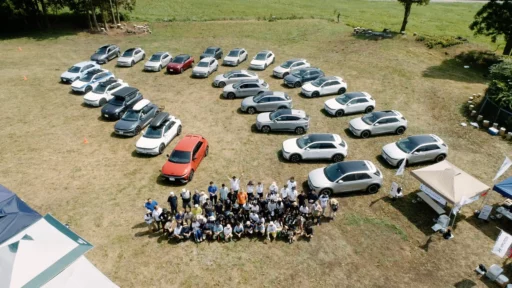 Grupo de personas y muchos autos en una campa.