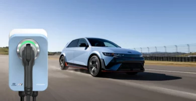 Coche eléctrico azul junto a estación de carga en pista.