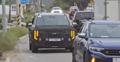 Vehículo en pruebas camuflado circulando por una carretera con tráfico.