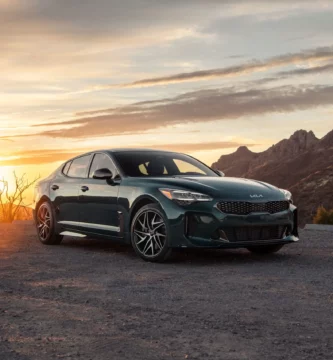 Coche en una carretera frente a la puesta de sol y montañas.