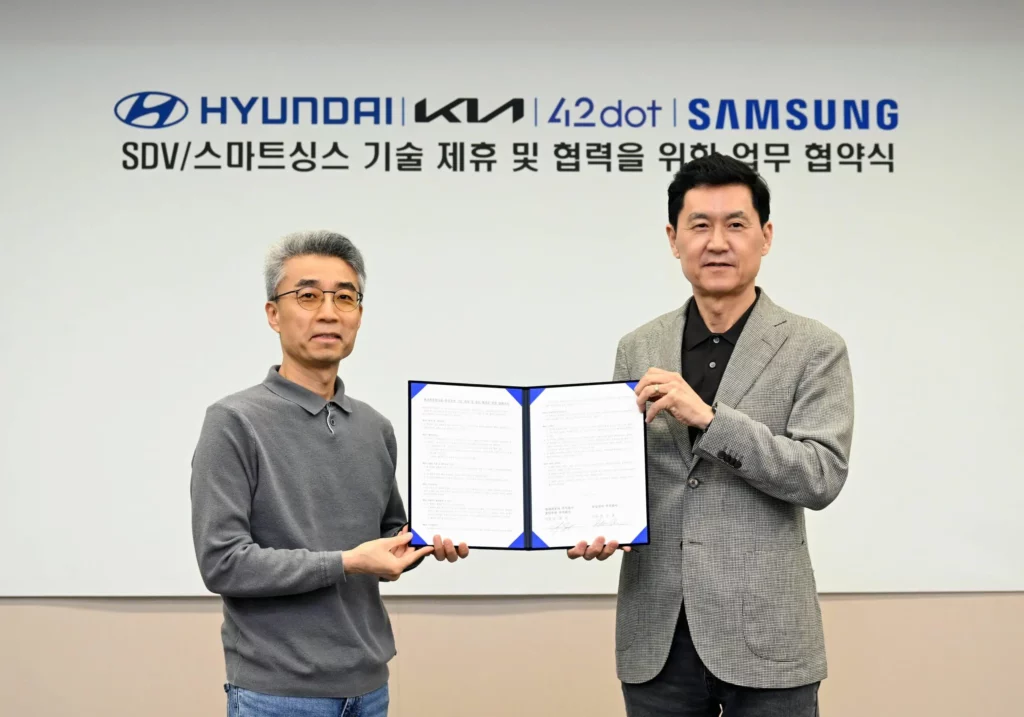 Dos hombres posan con un acuerdo firmado entre Hyundai y Samsung.