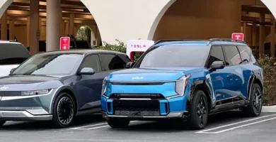 Dos coches eléctricos estacionados frente a estaciones de carga Tesla.