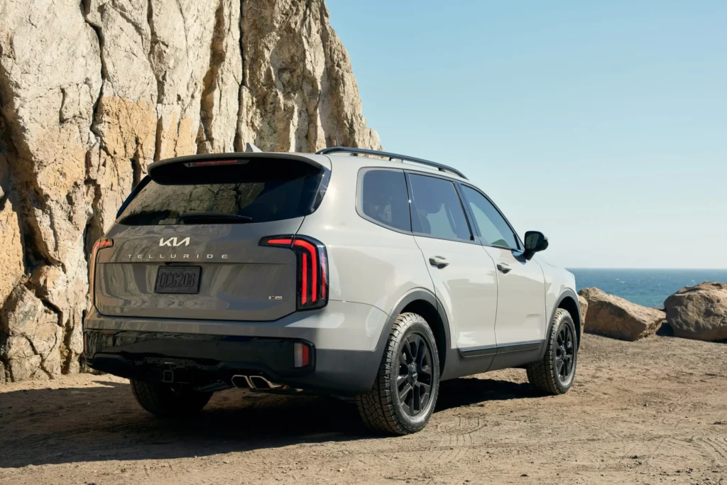 SUV gris estacionada junto a un acantilado rocoso junto al mar.