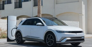 Auto eléctrico blanco cargando en una estación de Tesla.