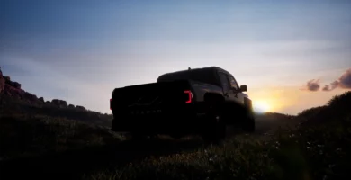 Camioneta negra al atardecer en un paisaje montañoso.