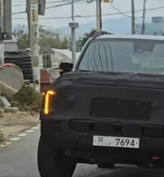 Auto con camuflaje circulando por una carretera urbana.