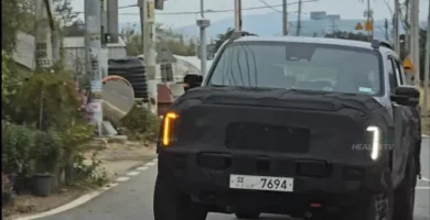 Auto con camuflaje circulando por una carretera urbana.