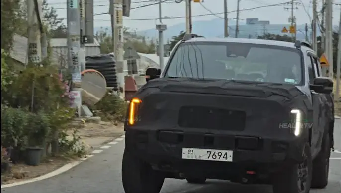 Auto con camuflaje circulando por una carretera urbana.