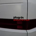 Parte trasera de un coche blanco con etiqueta "plug-in".