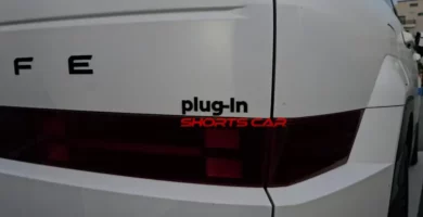 Parte trasera de un coche blanco con etiqueta "plug-in".