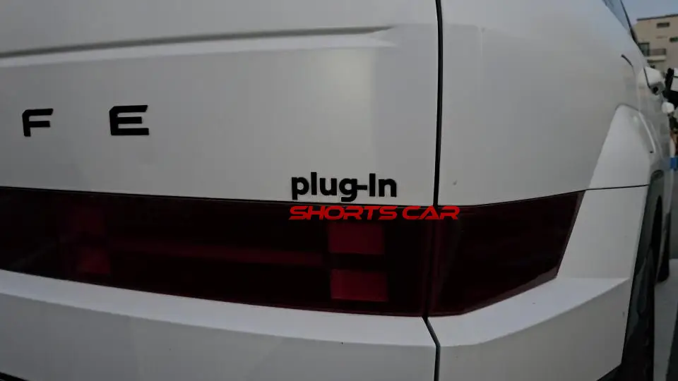 Parte trasera de un coche blanco con etiqueta "plug-in".