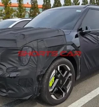 Auto camuflado con cubierta negra en un estacionamiento.