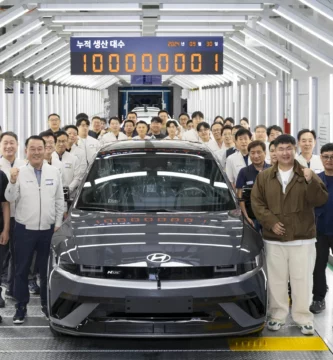 Un grupo de personas posando con un auto nuevo en una fábrica.