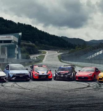 Seis coches deportivos en una pista de carreras con montañas.