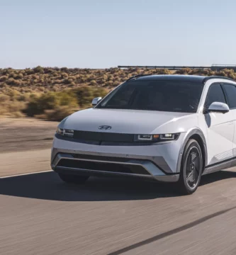 Coche blanco eléctrico en carretera desértica bajo cielo despejado.